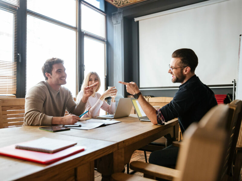 smiling-colleagues-sitting-near-coffee-while-work-with-laptops